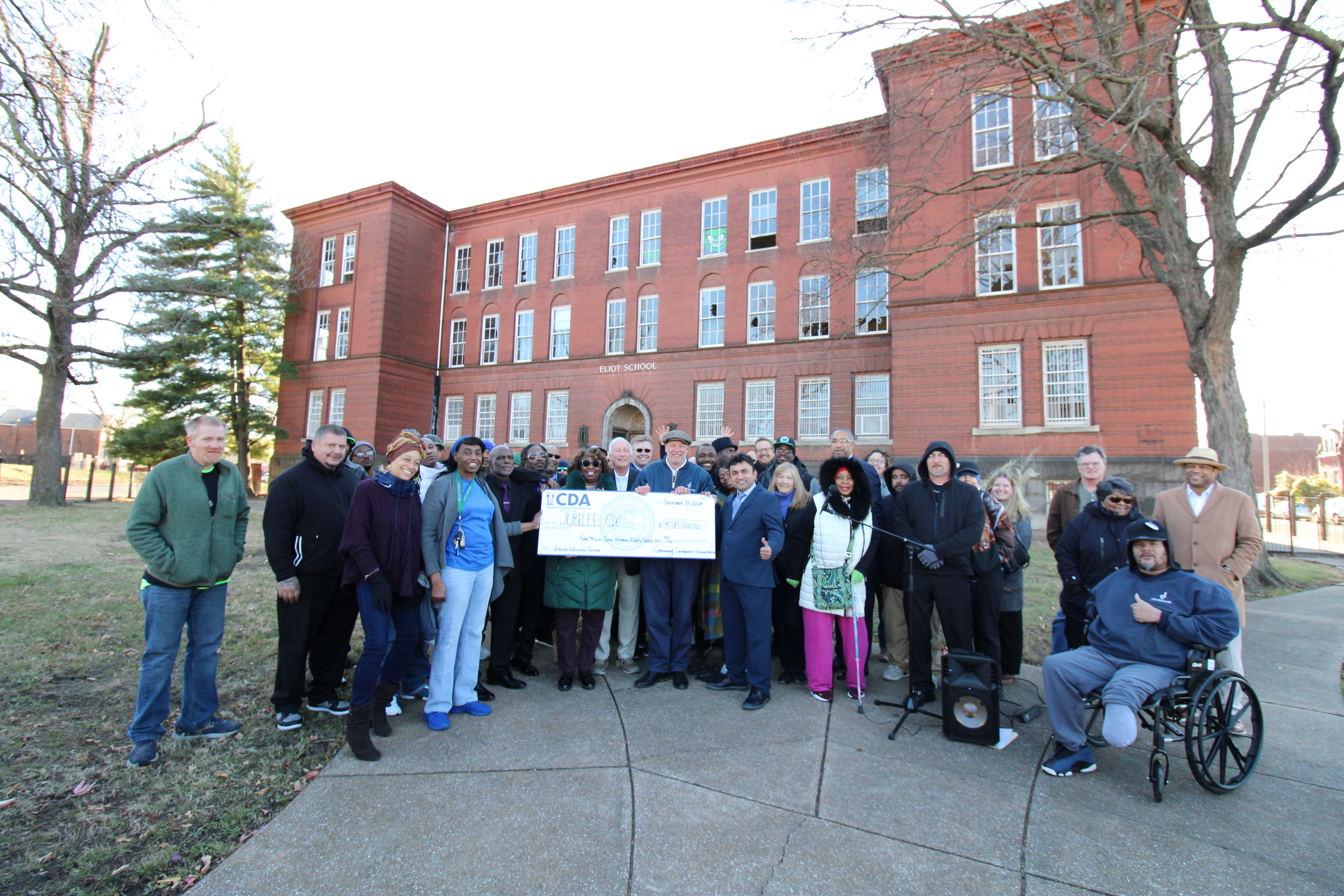Stakeholders outside front entrance of vacant Eliot Elementary School with CDA check.