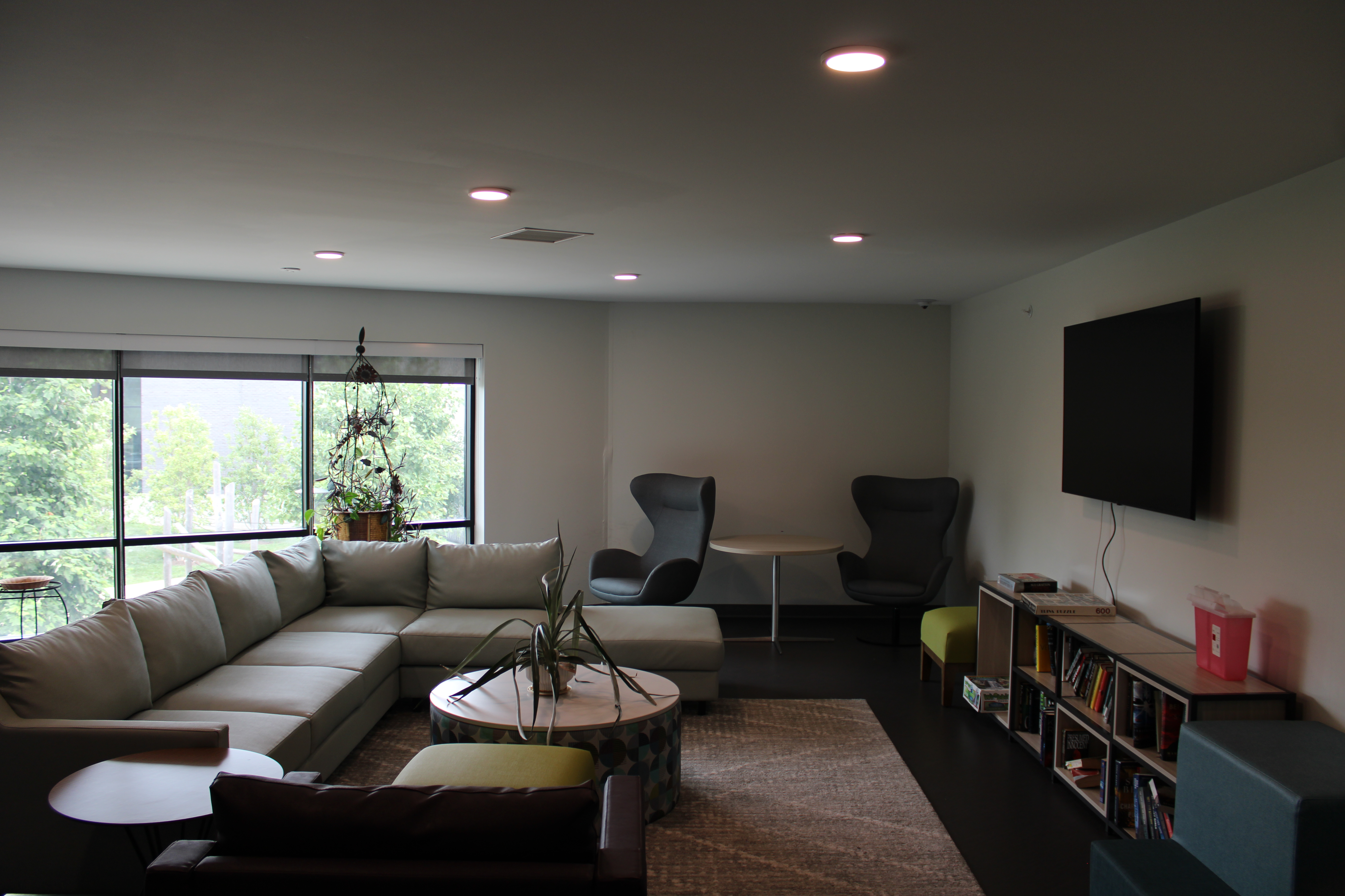 Common space in housing complex featuring a TV, couch, games, and books. 