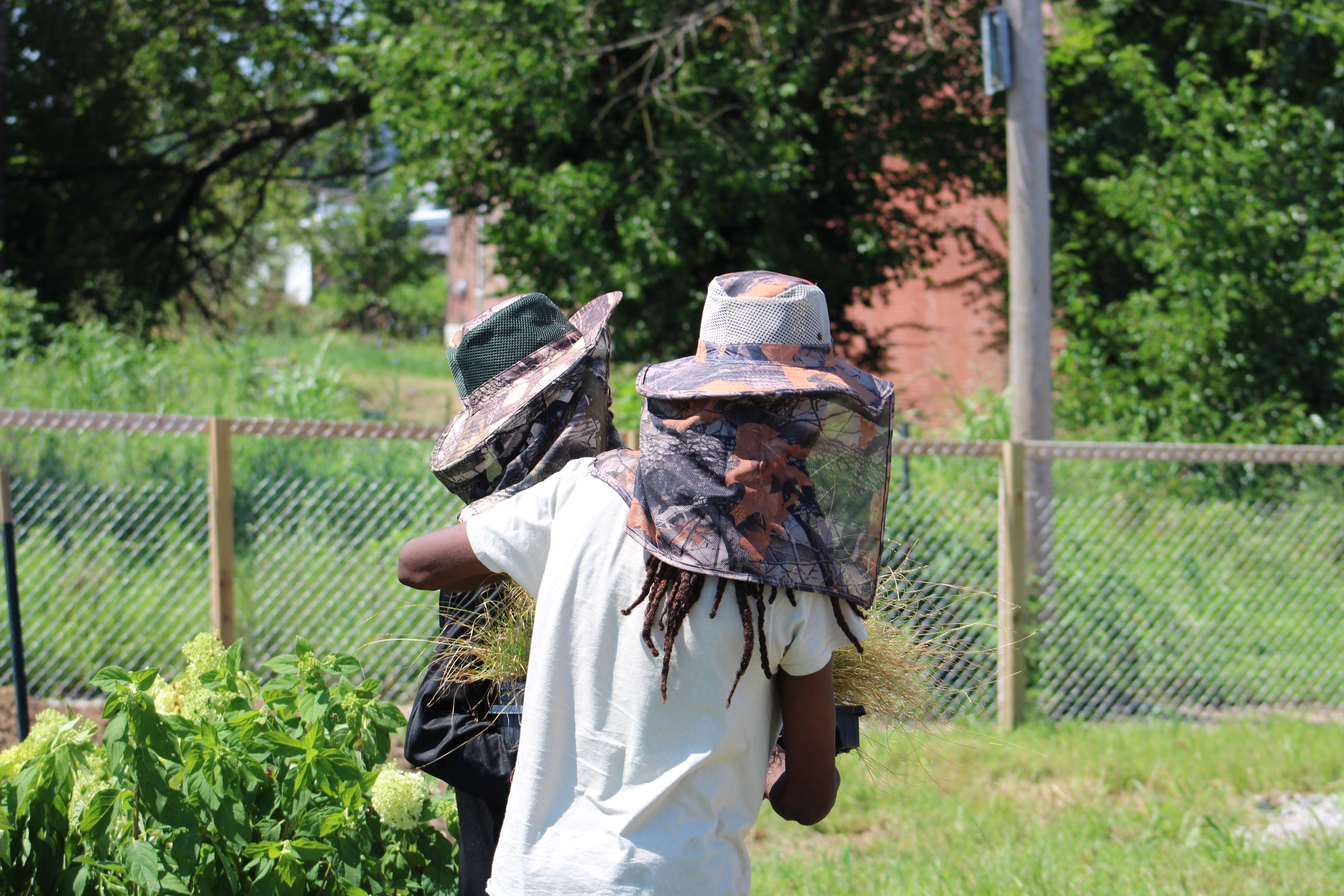 Two team members carrying plants and enjoying the sun.