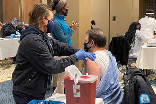 A man receiving a vaccine at a Health Department COVID-19 vaccine clinic