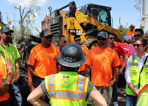 Mayor Spencer with her back to the camera talks to a group of City workers