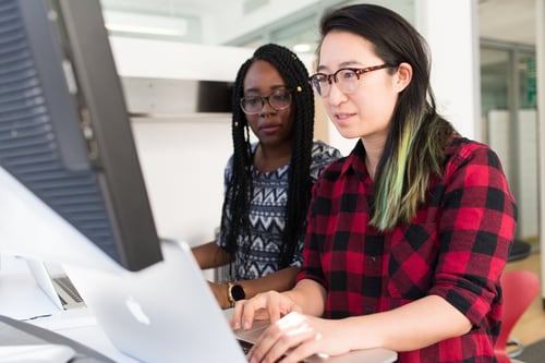 Two women using computers at a desk