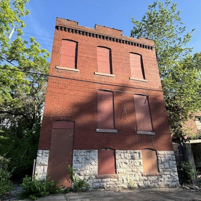 a two-story brick building with boarded-up windows
