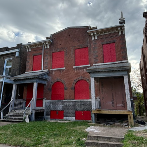 a two-story brick building with boarded-up windows