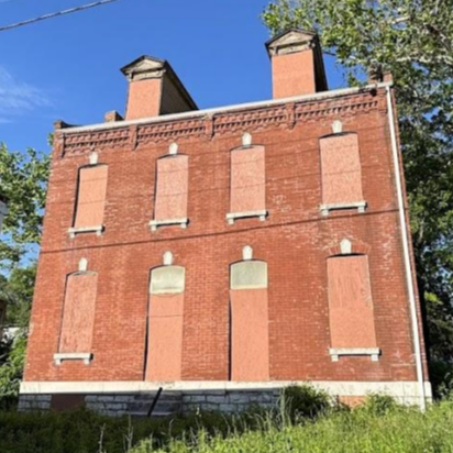 a three-story brick building with boarded-up windows