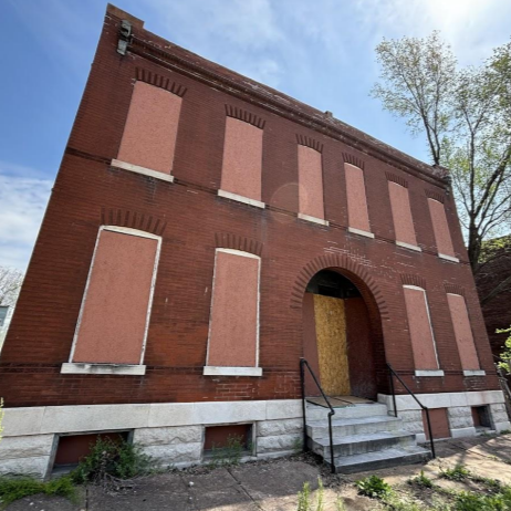 a two-story brick building with boarded-up windows