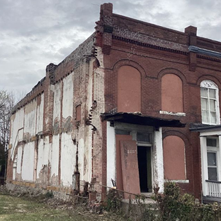 a two-story brick building with boarded-up windows