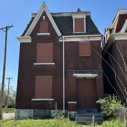 a three-story brick building with boarded-up windows