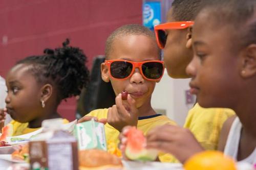 Young Child wearing orange "No Kid Hungry" sun glasses